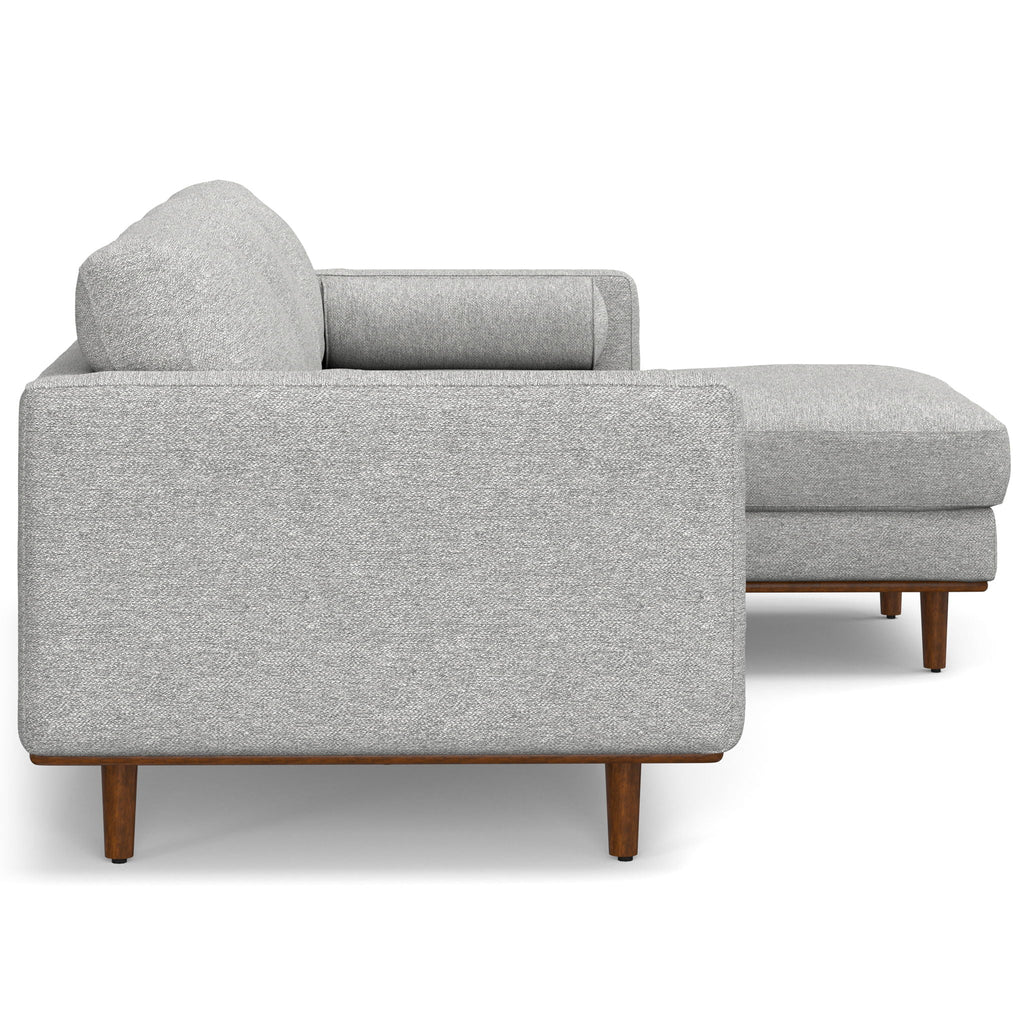 Light gray upholstered sectional sofa with chaise, rounded back, and block feet