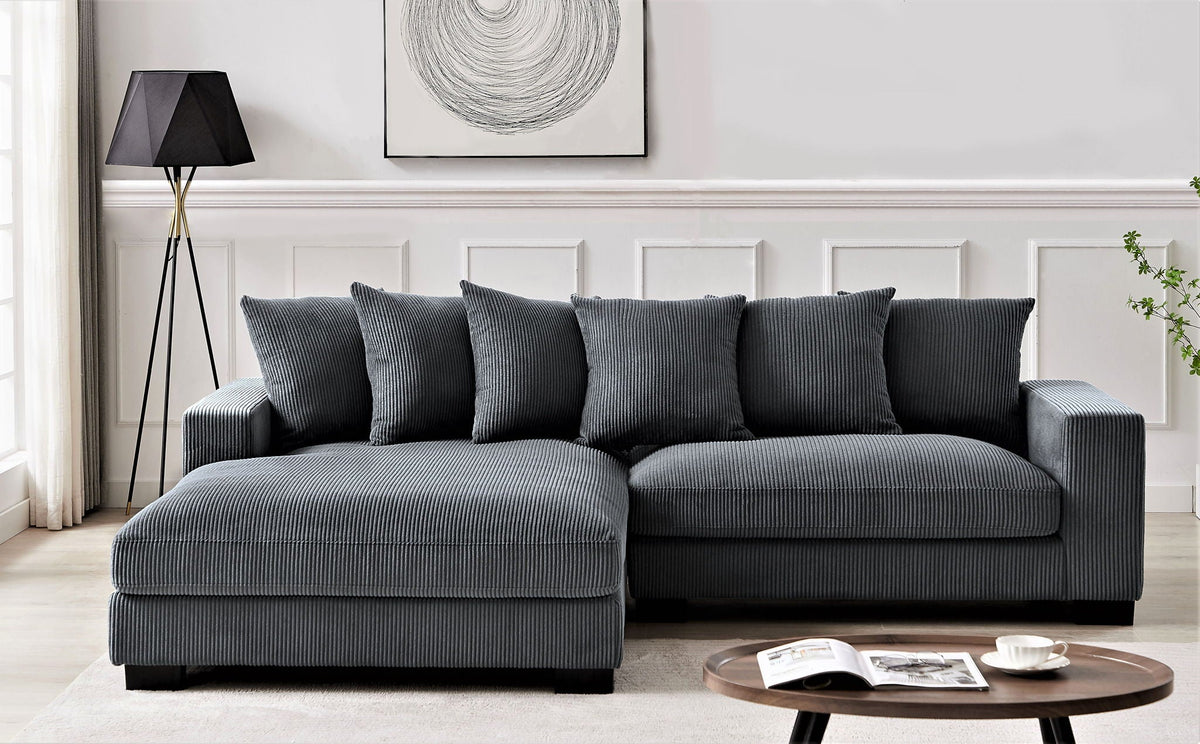L-shaped sectional sofa with chaise, dark gray corded upholstery and decorative pillows