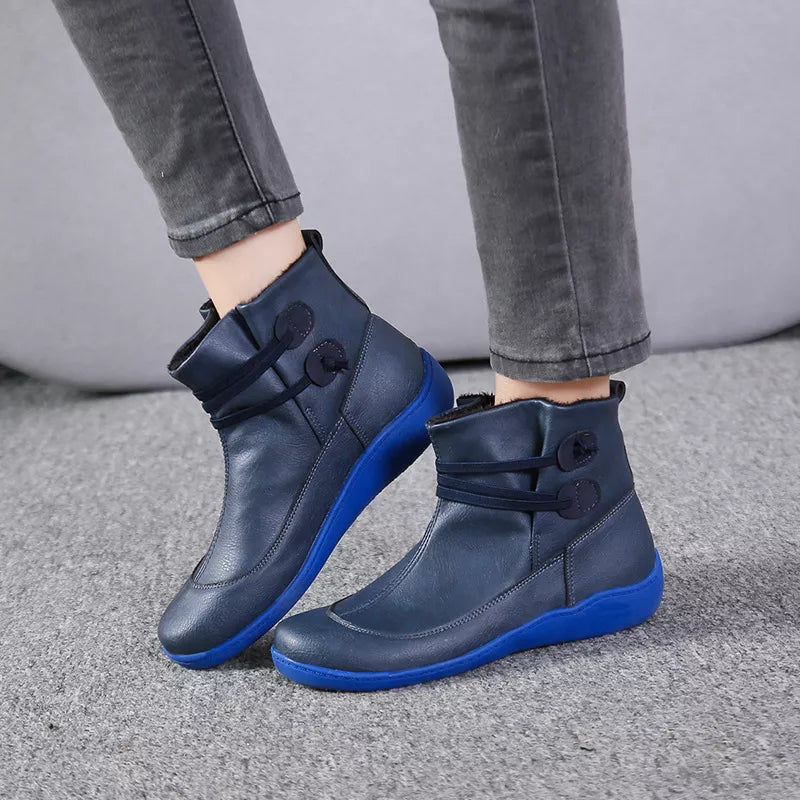 Navy button-detail ankle boots with side straps, cushioned collar, and blue sole.