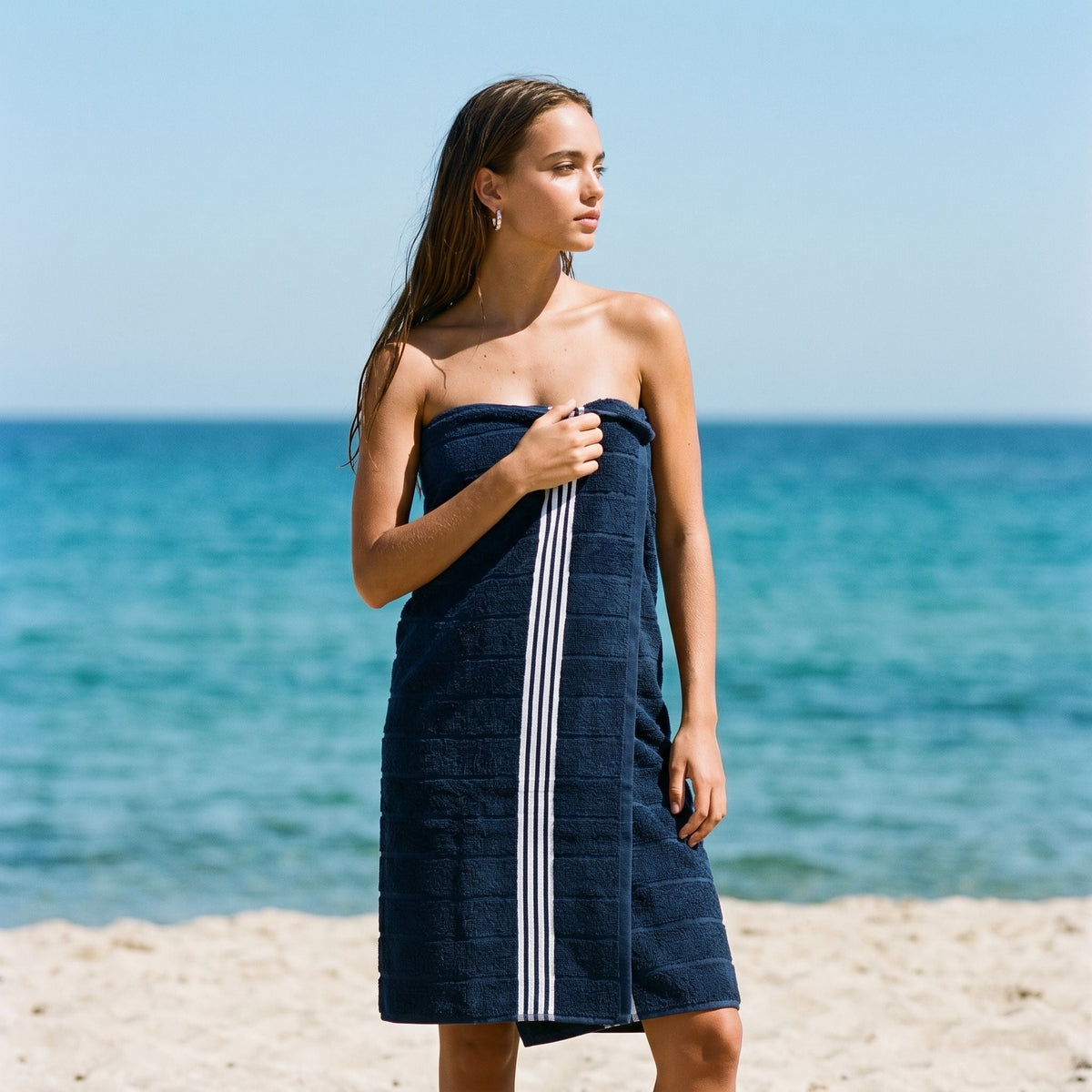Navy cotton towel with white stripe border, worn as a wrap on a model