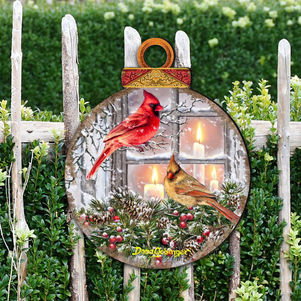 Large round outdoor ornament with red cardinal and yellow bird hanging in a garden