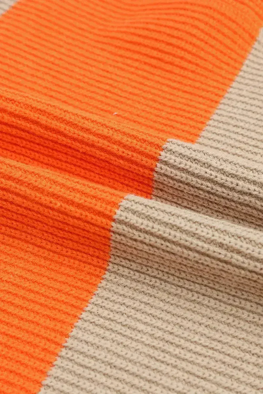 Close-up of orange and beige ribbed knit texture on colorblock cardigan fabric