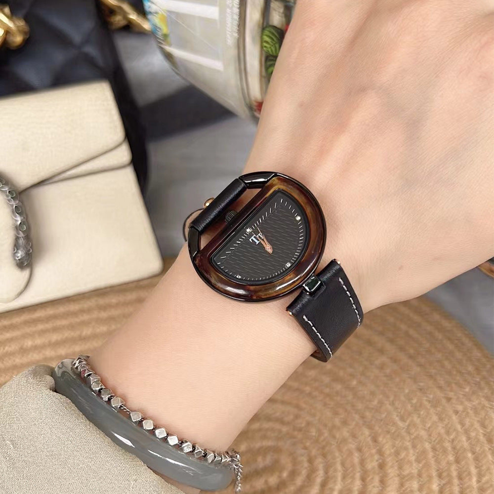 Women’s leather-strap watch with dark brown band and bronze-toned oval case, dark dial.