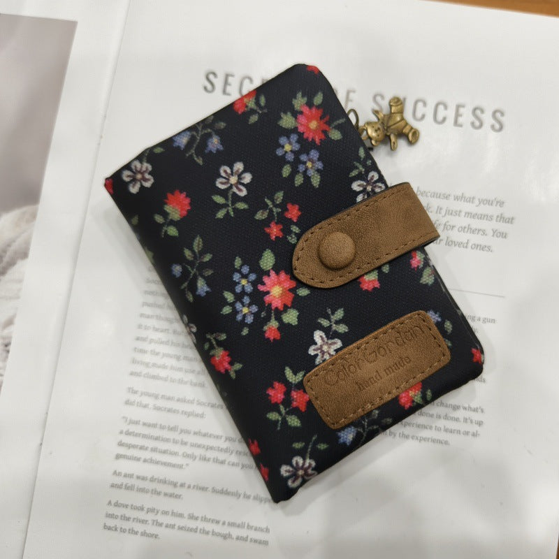 Tri-fold wallet with dark floral print, top clasp and front card pockets