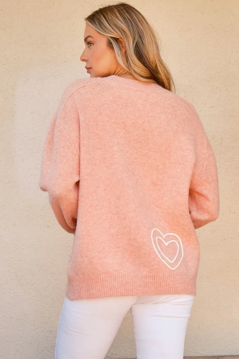 Pink round-neck sweater with heart outline graphic on the back hem