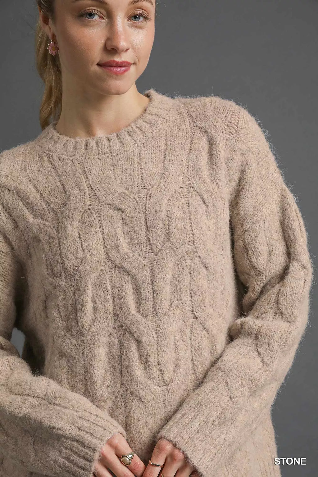 Stone cable-knit sweater close-up with cable texture, crew neck, ribbed cuffs