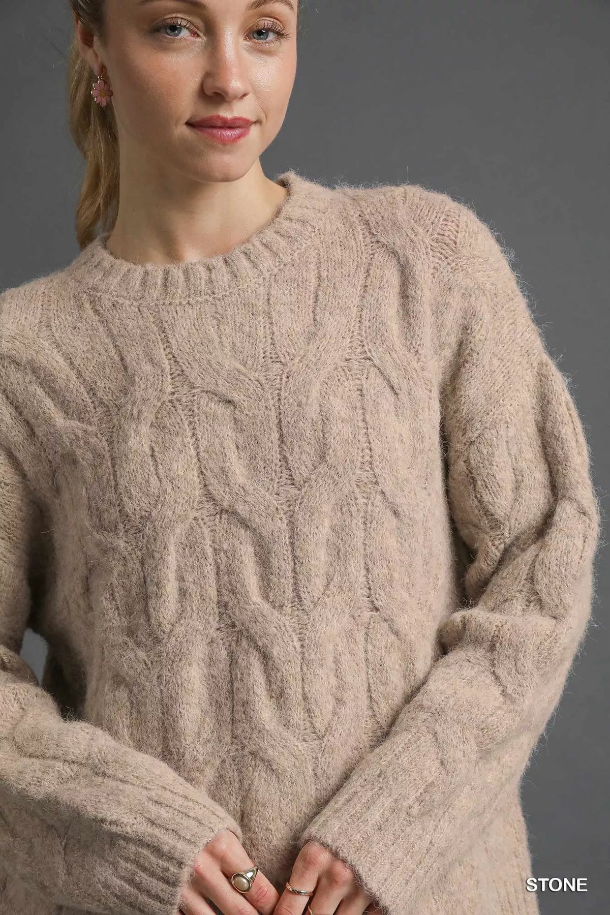 Stone cable-knit sweater close-up with cable texture, crew neck, ribbed cuffs