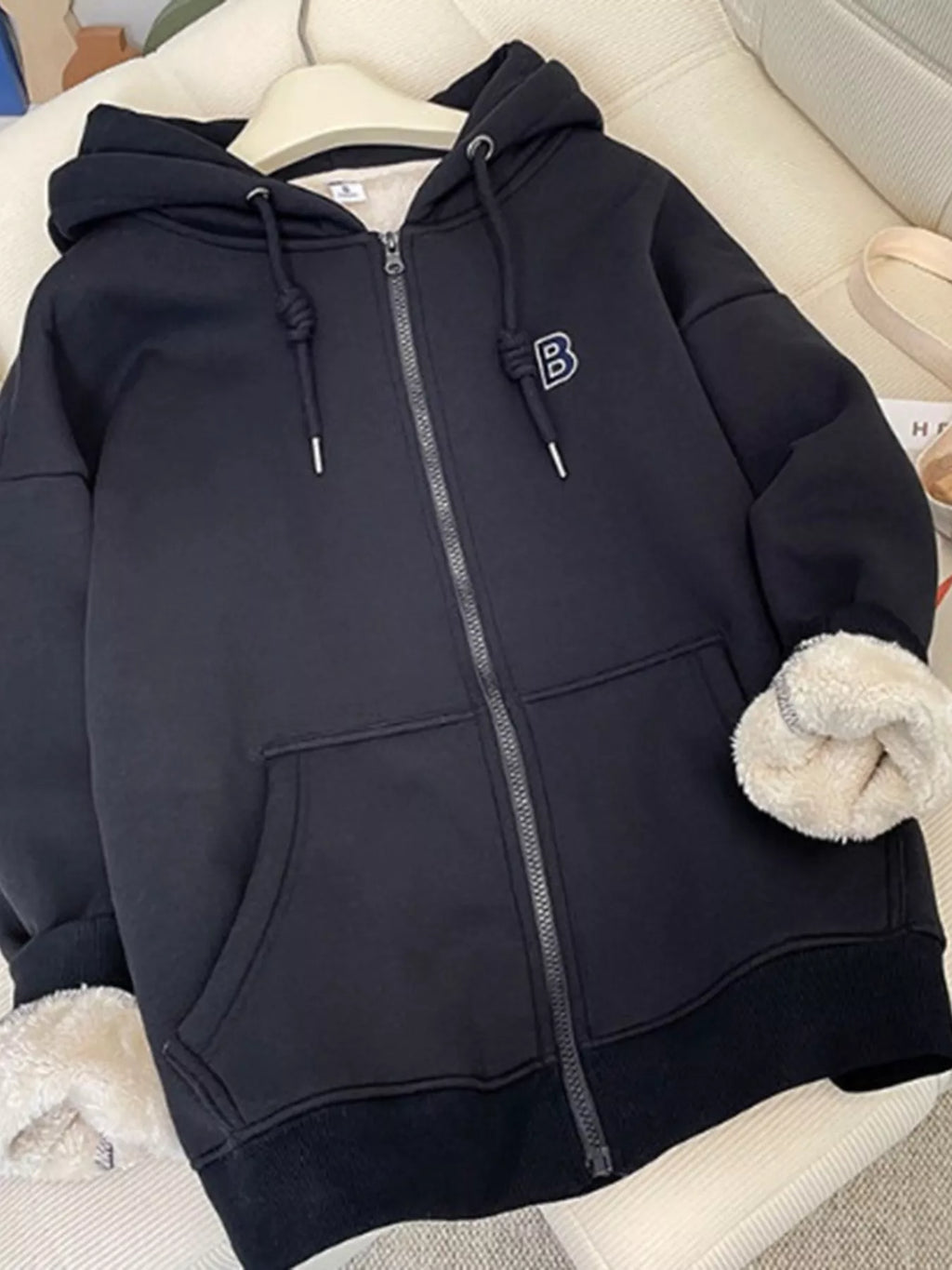 Black fleece-lined zip-up hoodie front view: hood, zipper, kangaroo pocket, drawstrings.