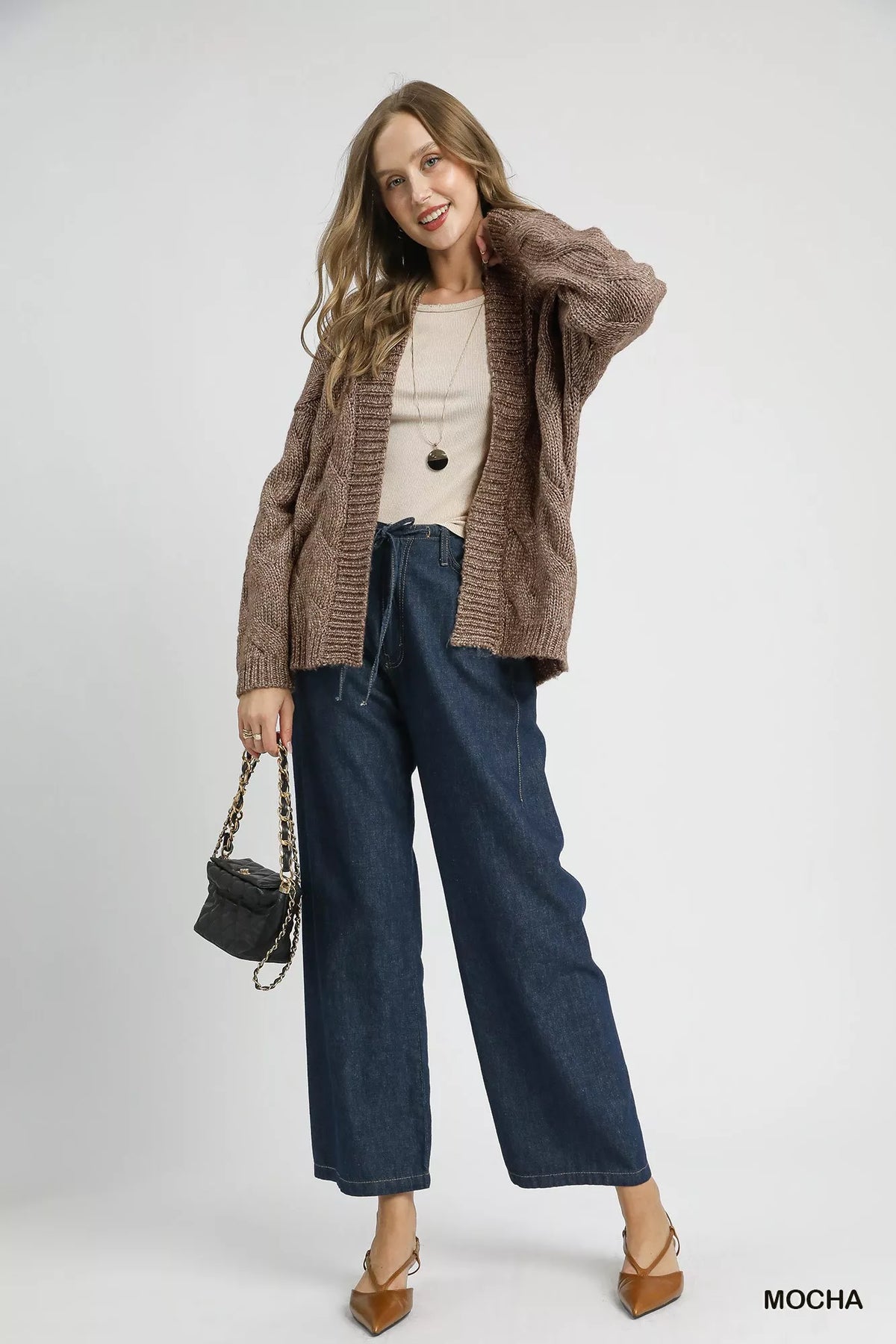 Mocha cable-knit open-front cardigan worn over dark jeans, long sleeves