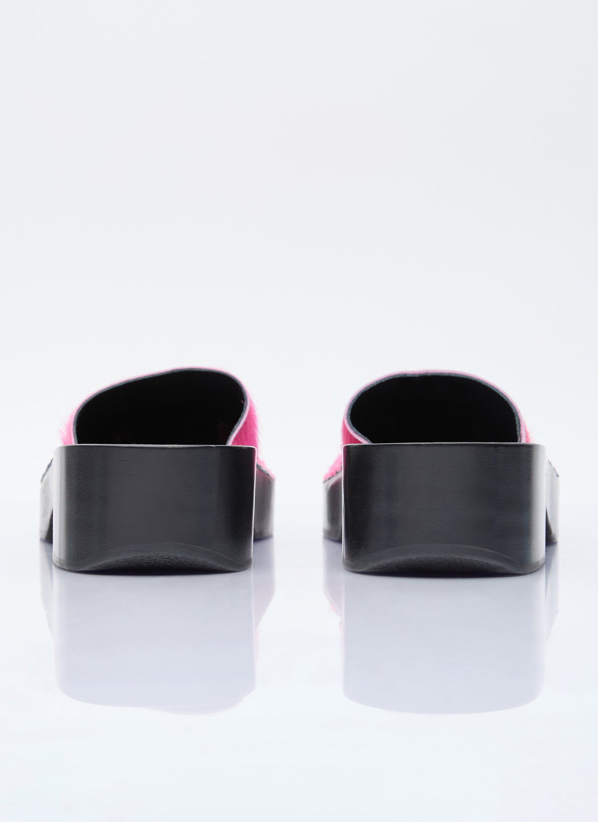 Pair of pink furry clogs with black open backs and cushioned insoles