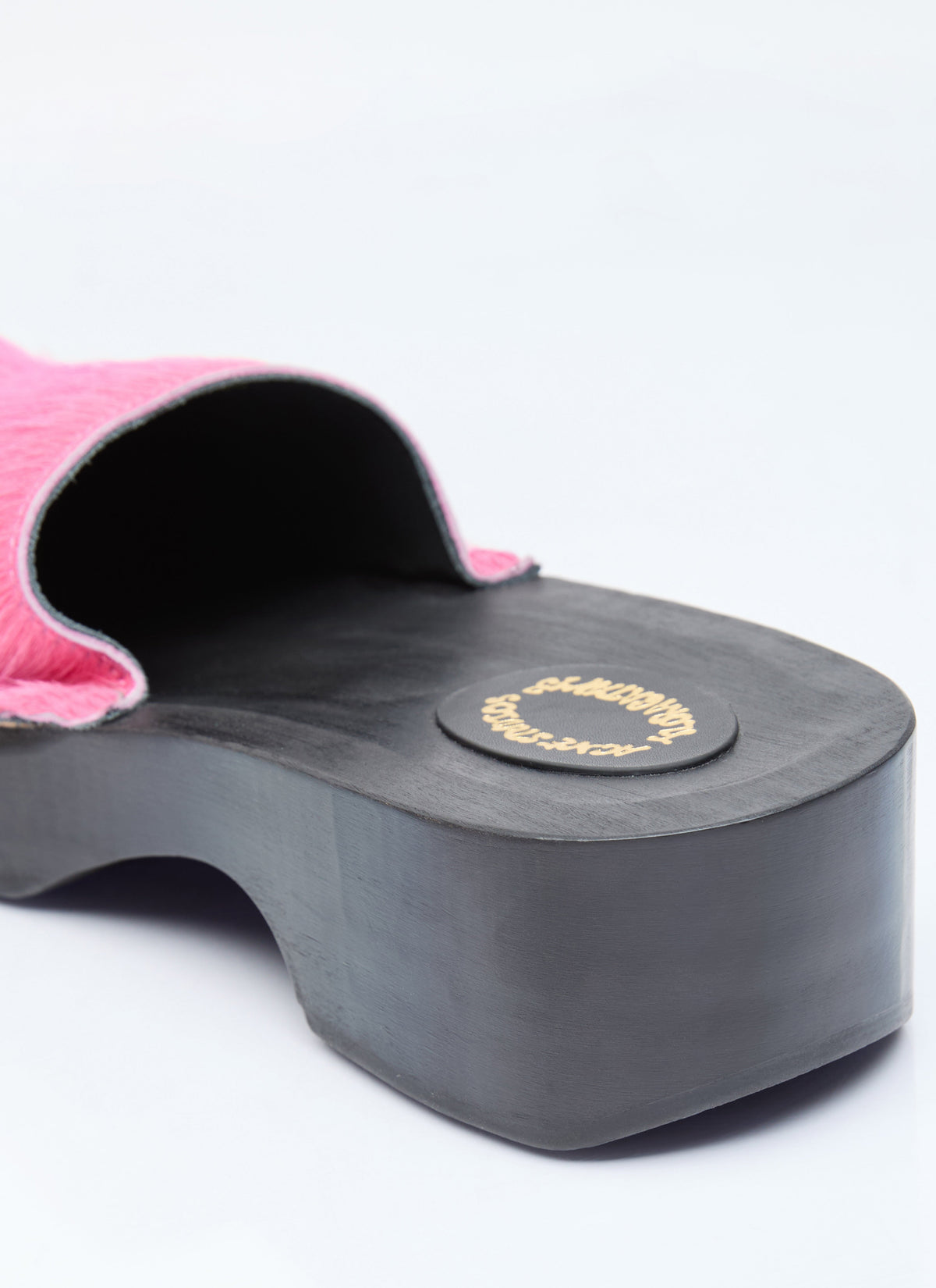 Black platform sole of pink furry clog with gold logo on footbed
