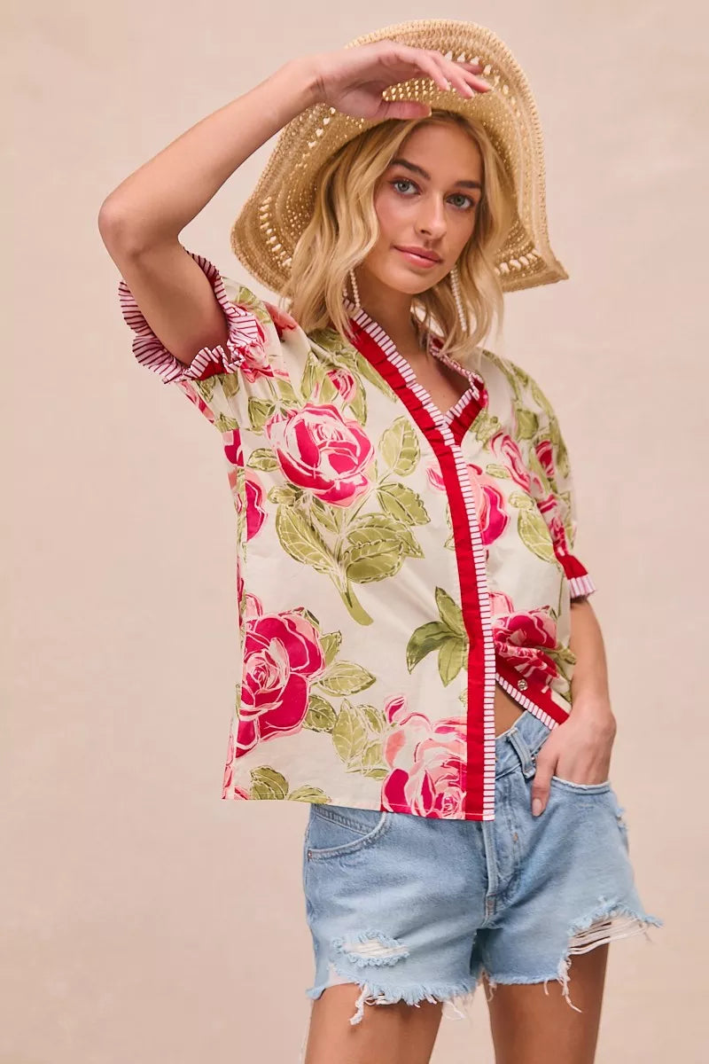Floral printed blouse with coral contrast trim, ruffled cuffs, and short sleeves