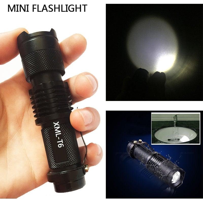 Compact mini LED flashlight held in hand, black textured body with lanyard loop and bright beam