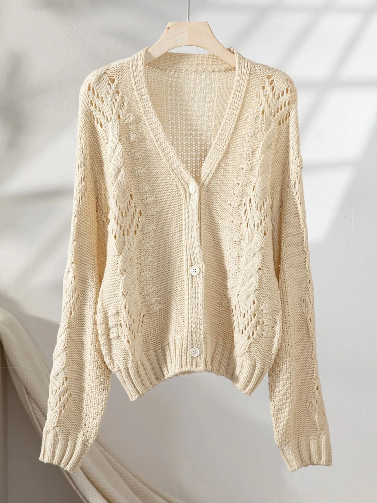 Beige cropped cable-knit cardigan, front view: V-neck and button closure