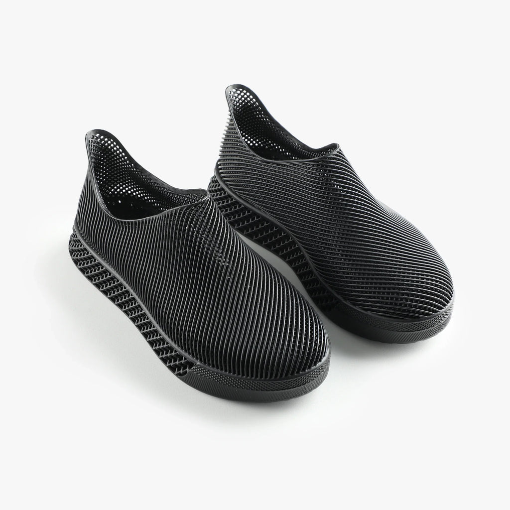 Pair of black 3D printed slip-on sneakers with ribbed upper and cushioned sole