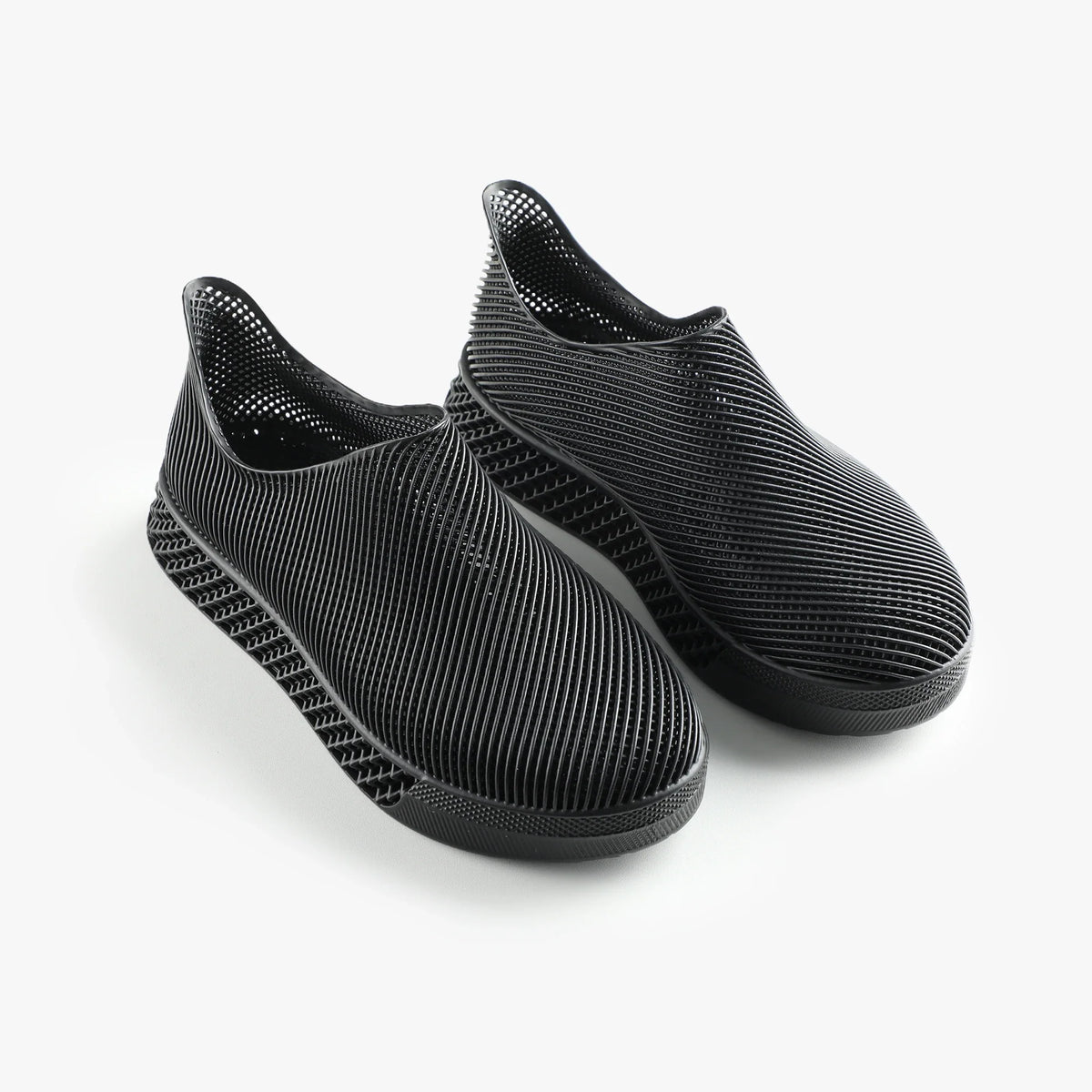 Pair of black 3D printed slip-on sneakers with ribbed upper and cushioned sole
