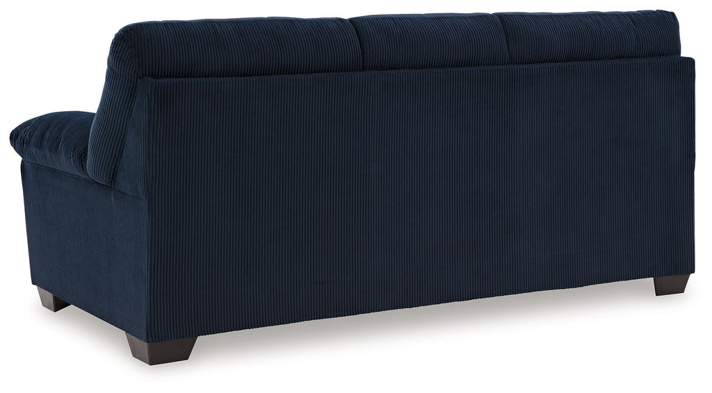 Upholstered sofa in blue fabric, angled back view with plush arms and tufted back
