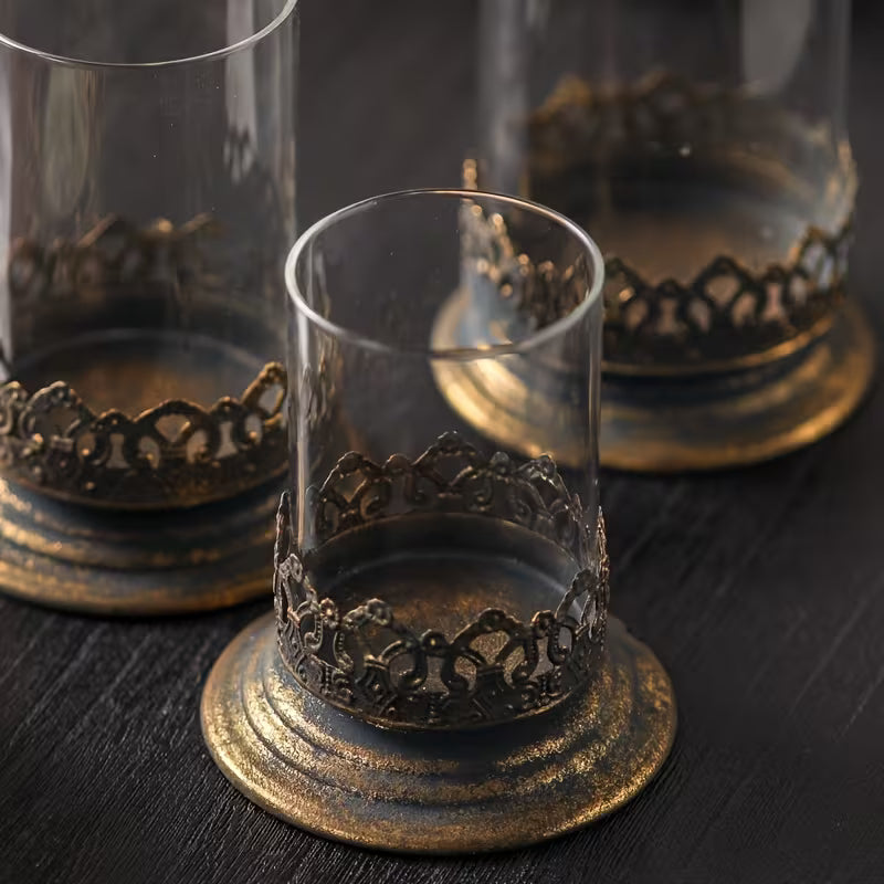 Glass candle holder with clear cylinder and ornate dark metal base band