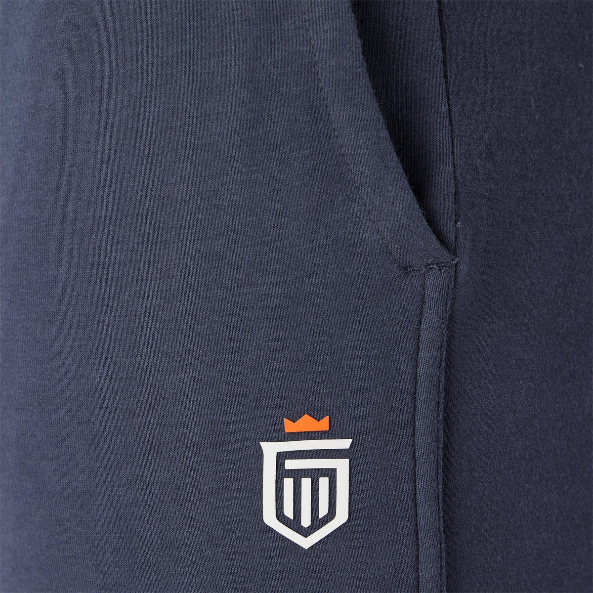 Navy jogger pants close-up of shield logo on the leg.