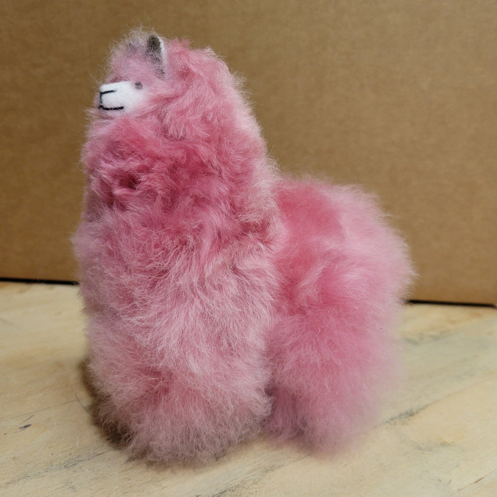 Pink fuzzy plush animal with black eyes, sitting pose
