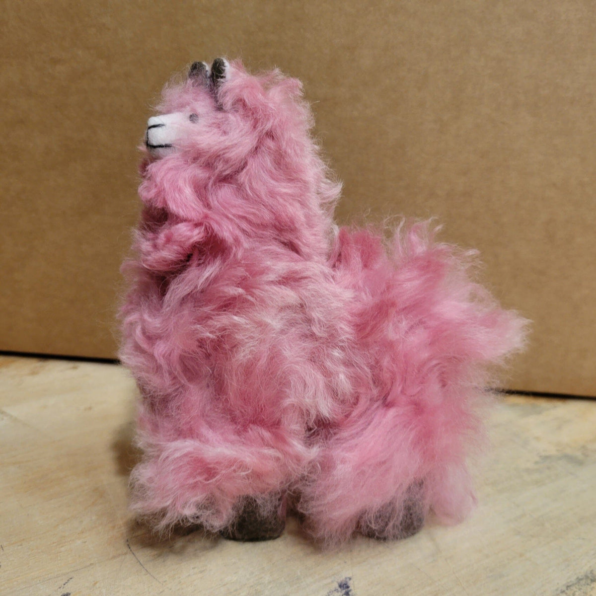 Pink fuzzy plush animal with black eyes and nose