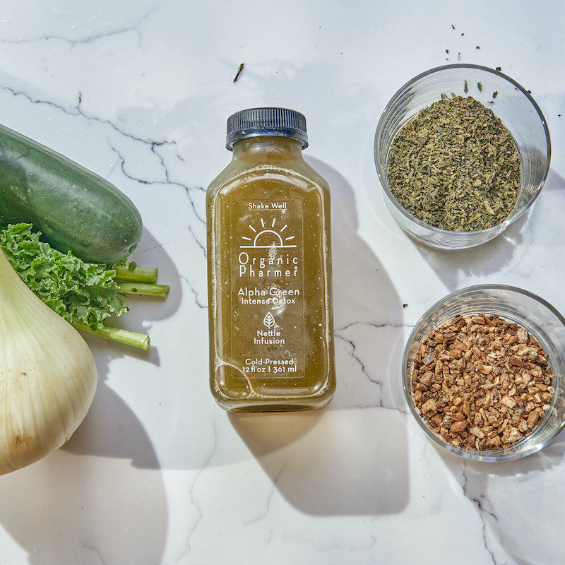 Organic botanical beverage bottle with two bowls of dried herbs on marble