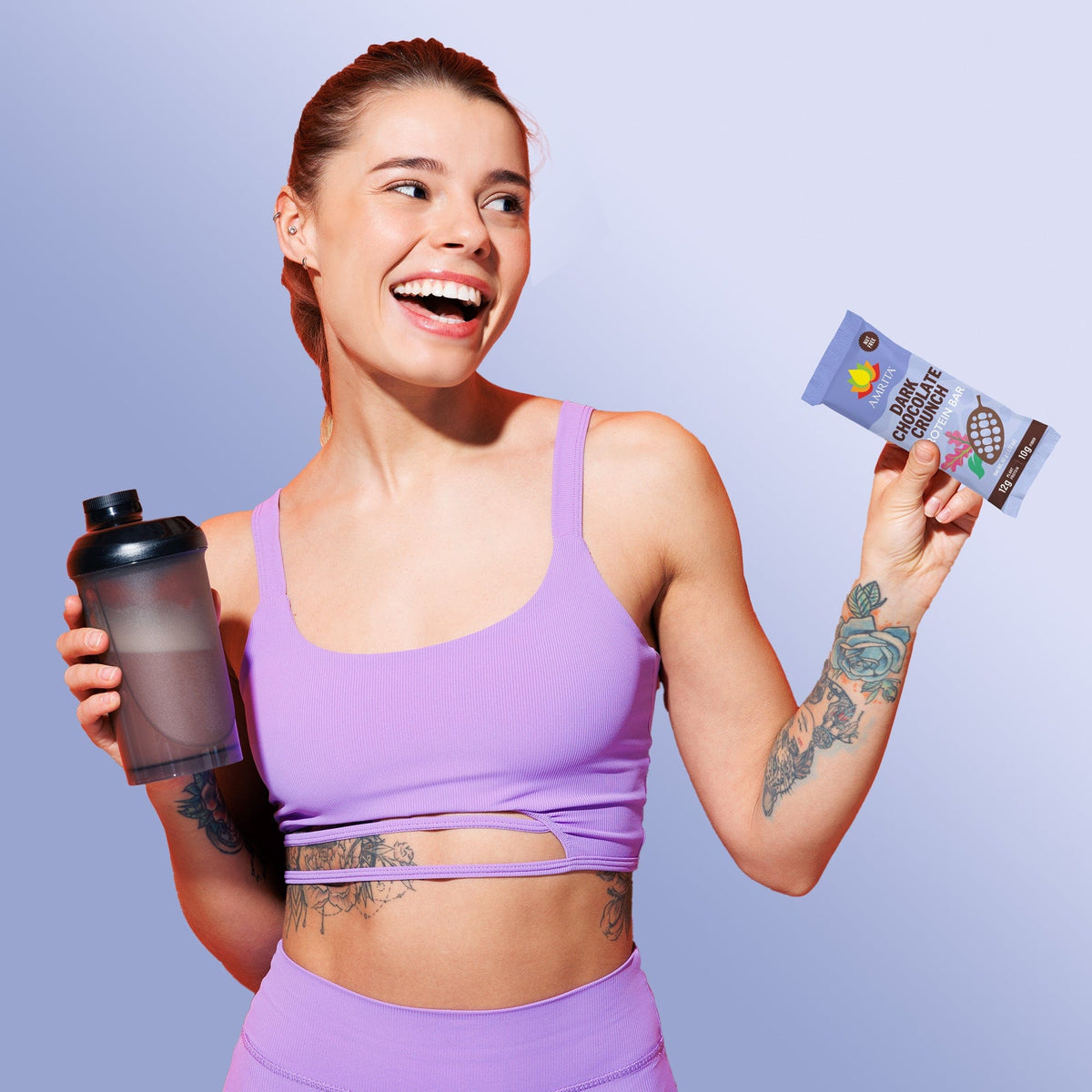 Woman holding a wrapped dark chocolate protein bar with AMRITA logo