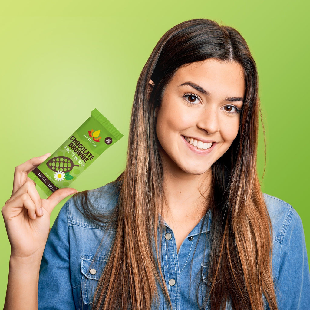 Chocolate brownie protein bar in green pouch held in hand with blue denim shirt
