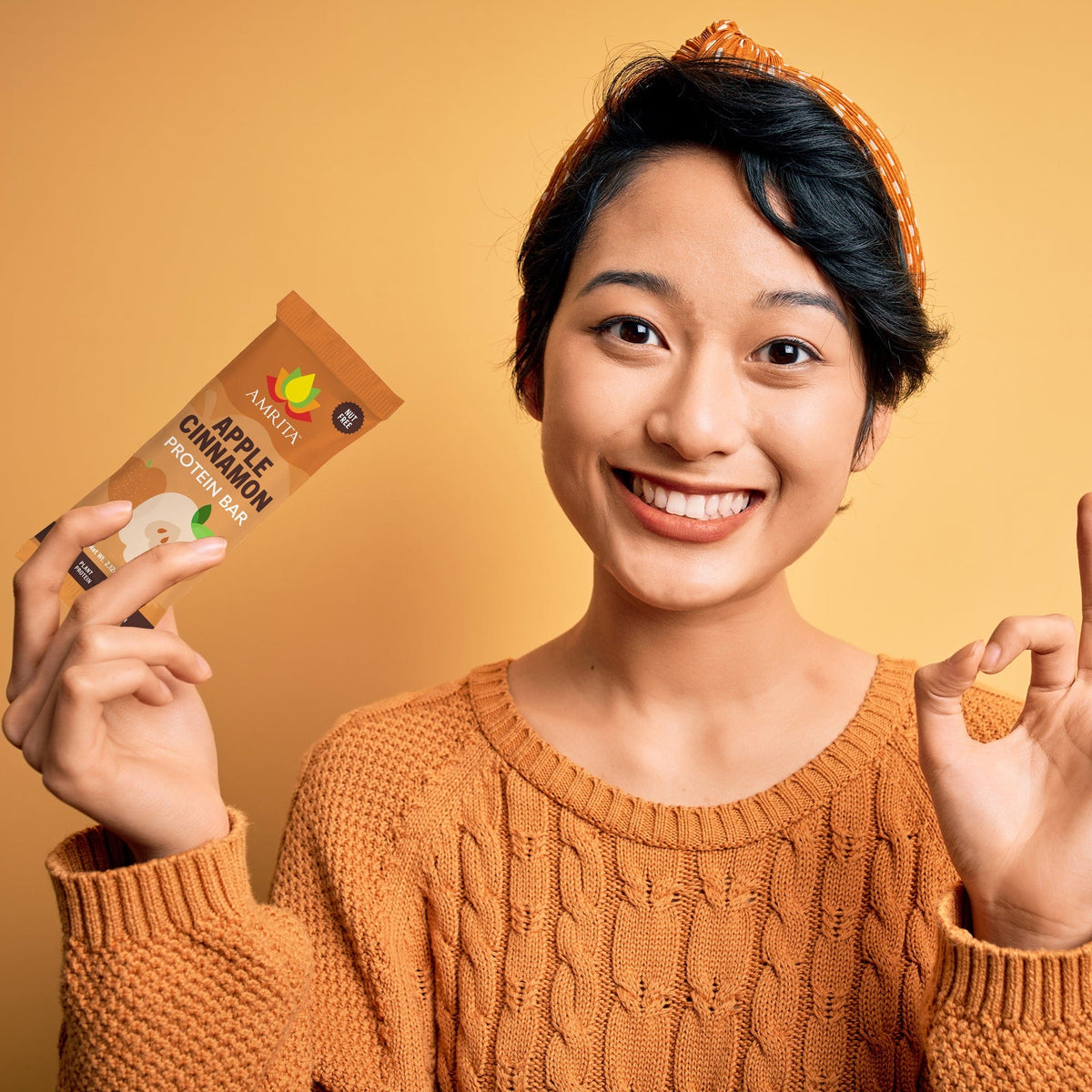 AMRITA protein bar pouch and bar piece held by a person