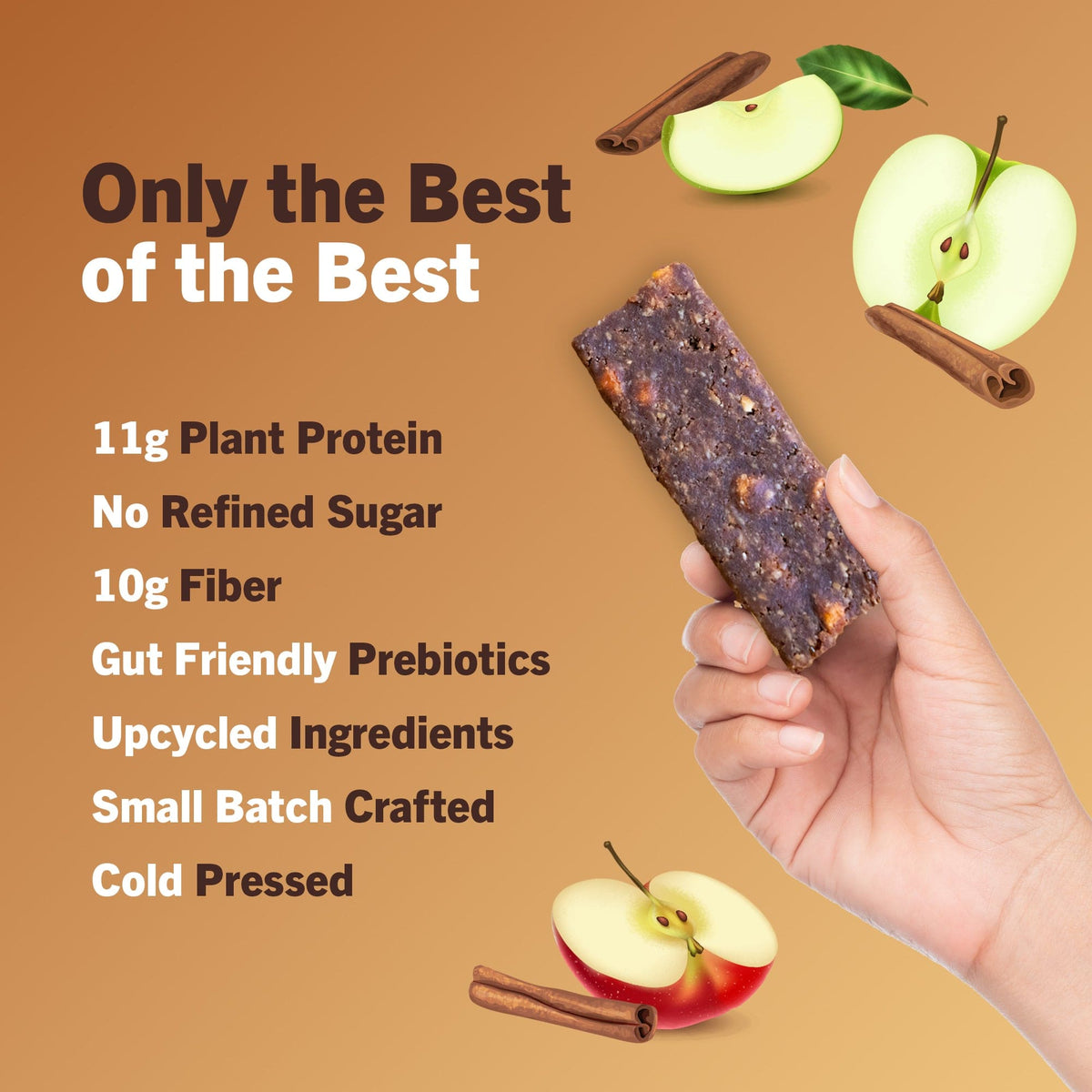 Hand holding AMRITA apple-cinnamon protein bar pieces with apple and cinnamon accents