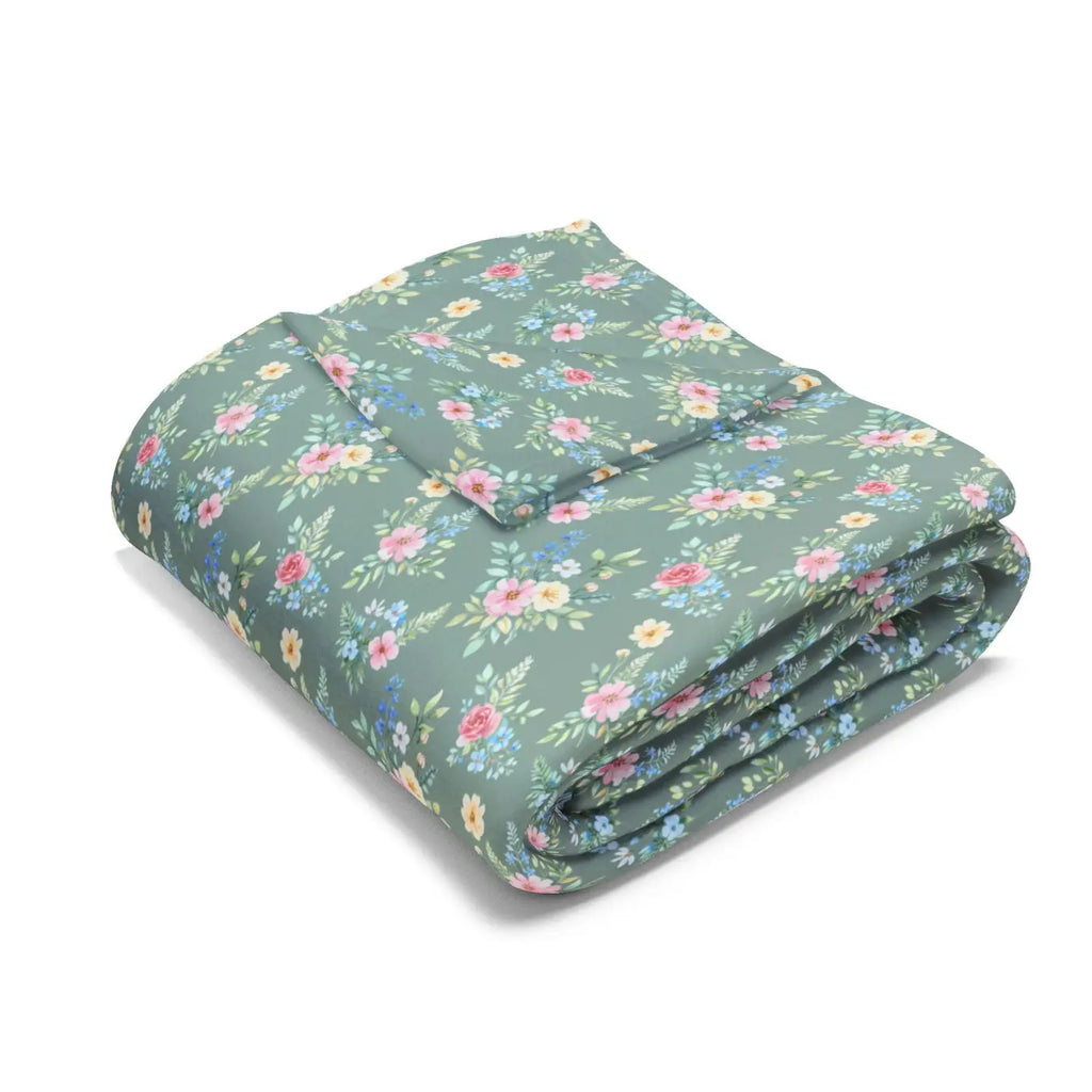Pastel floral fleece blanket folded, muted teal-green with pink, yellow, and blue flowers