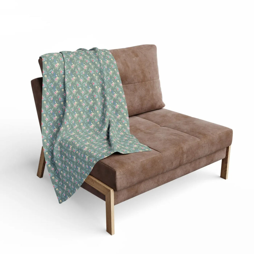 Pastel floral fleece blanket draped on a sofa, gray-green base with pink flower print
