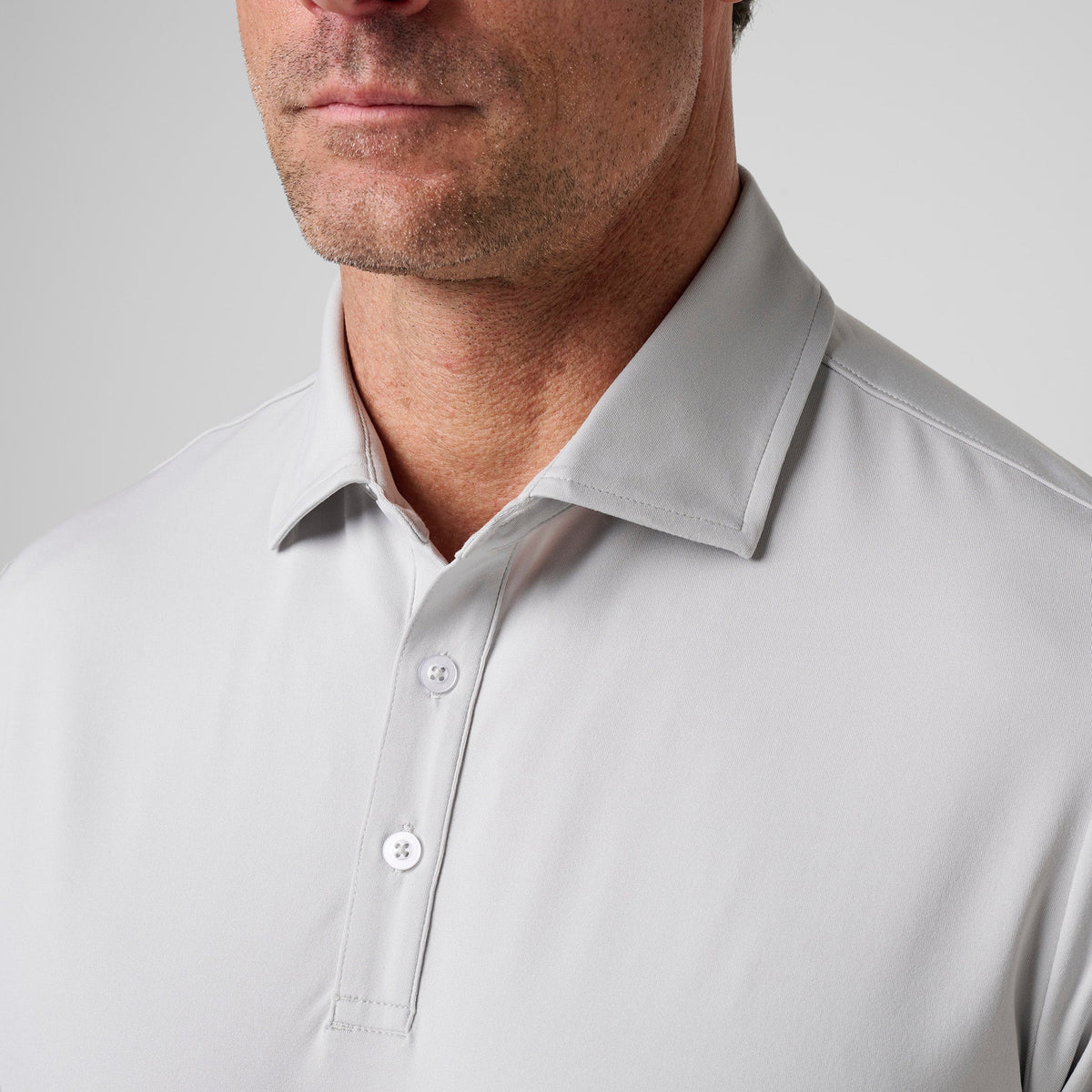 Ash gray polo close-up with short button placket and fold-over collar.