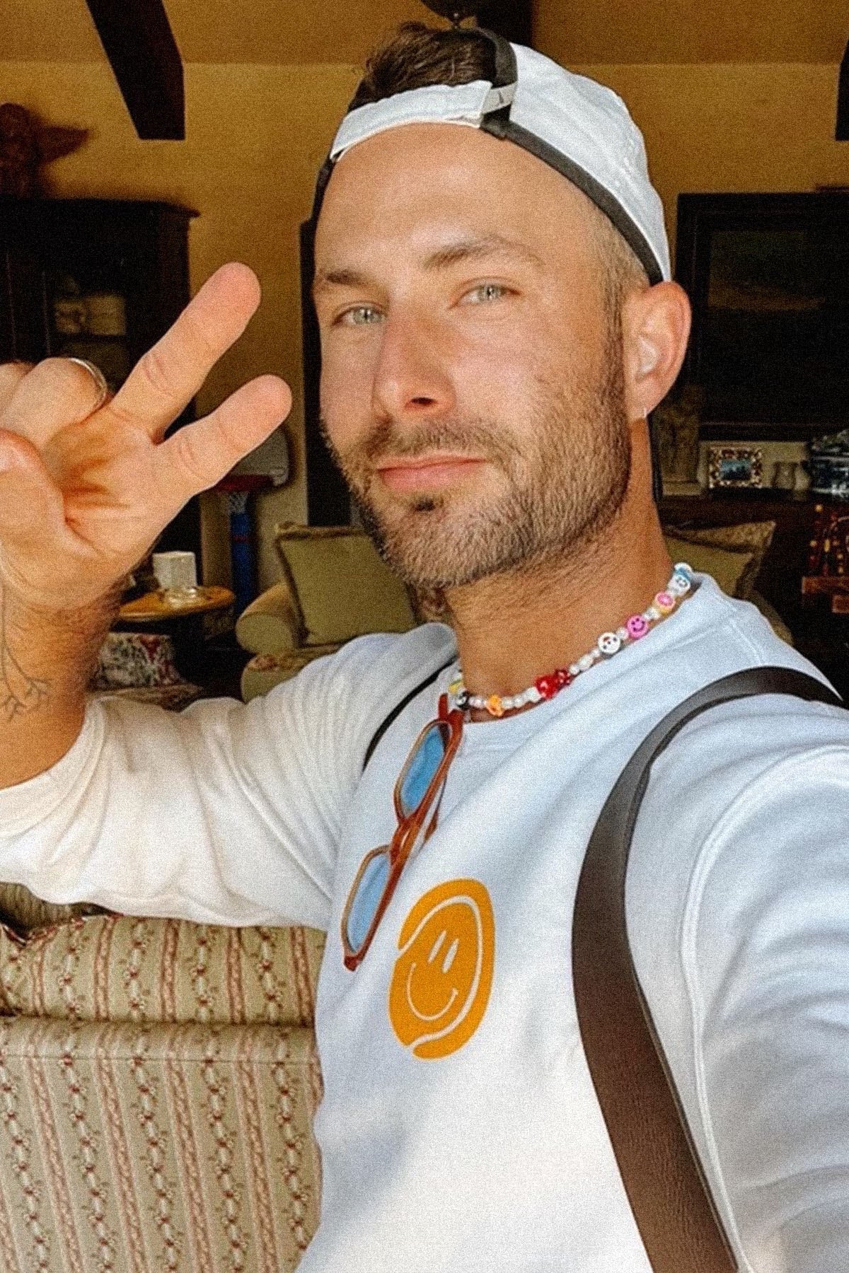 White crewneck sweatshirt with orange smiley face logo on the chest