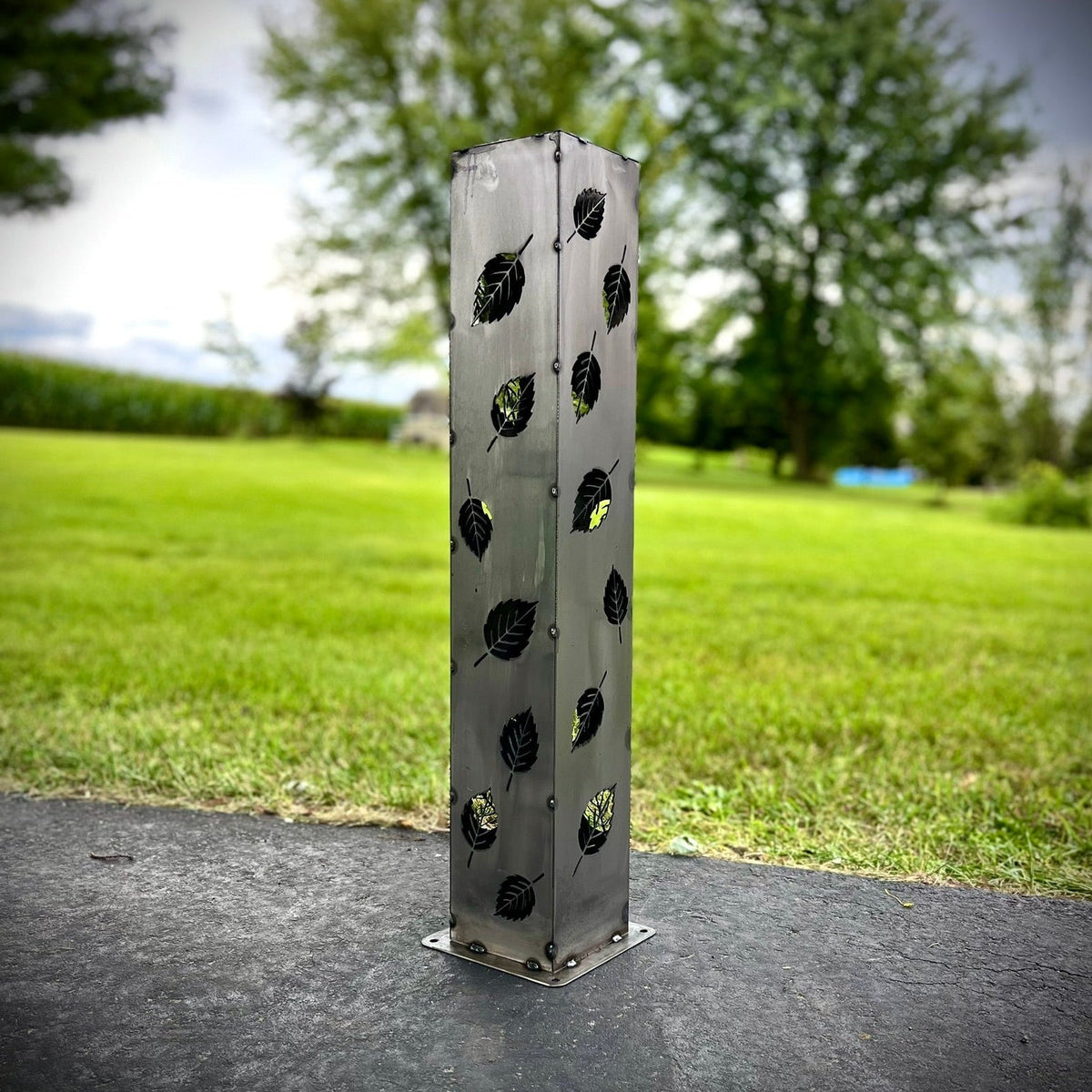 Silver metal solar pillar luminary with leaf cutout pattern and base mount