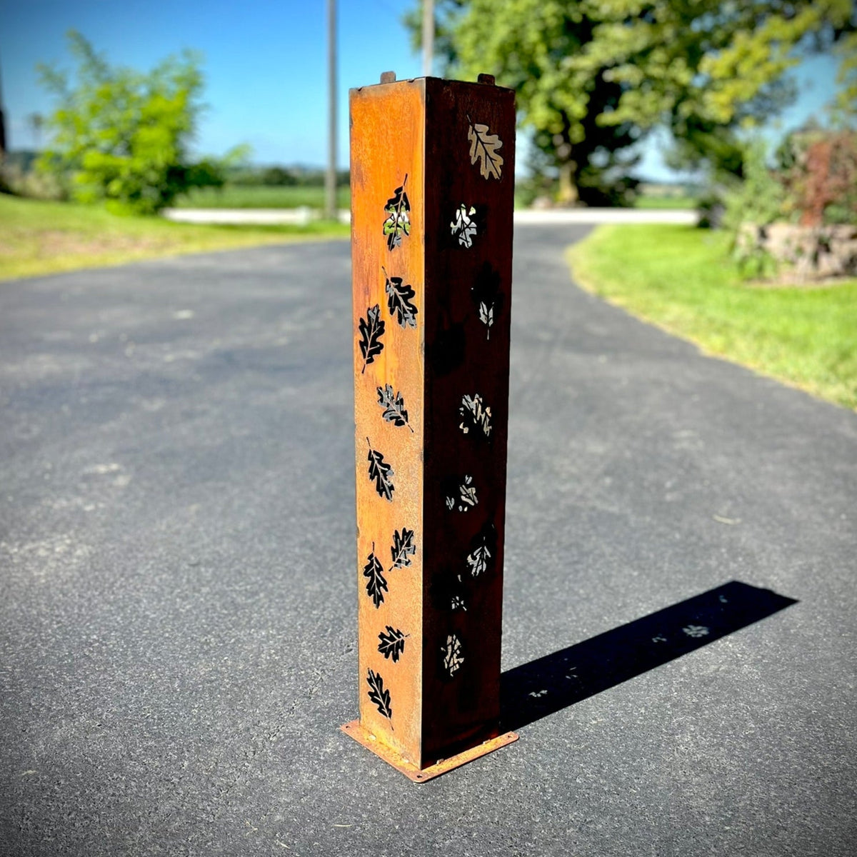 Orange and dark rust solar pillar luminary with leaf cutout pattern on metal post