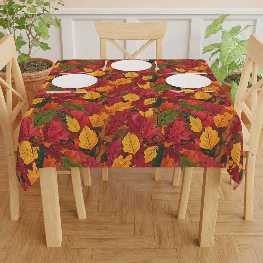 Autumn leaf-print tablecloth covering a dining table with plates at the center
