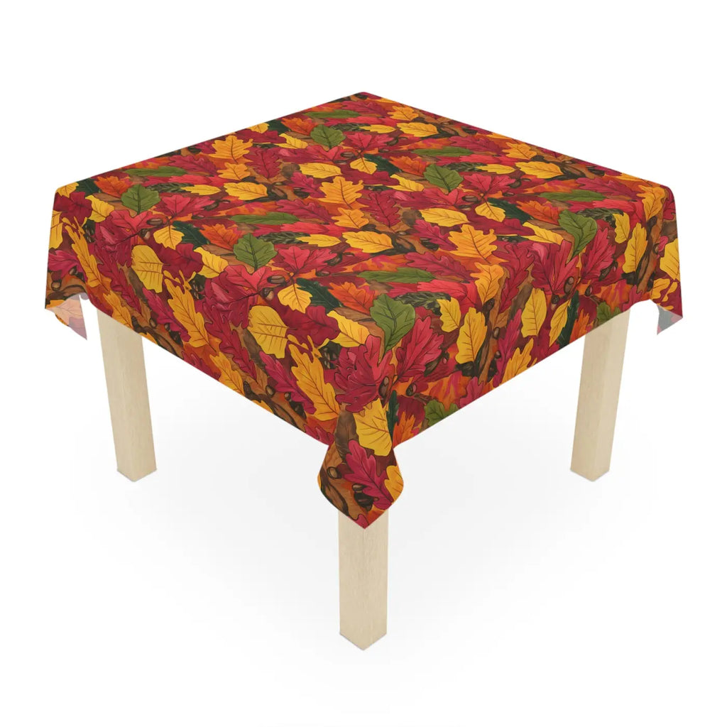 Corner drape of autumn leaf-patterned tablecloth over light wood table legs