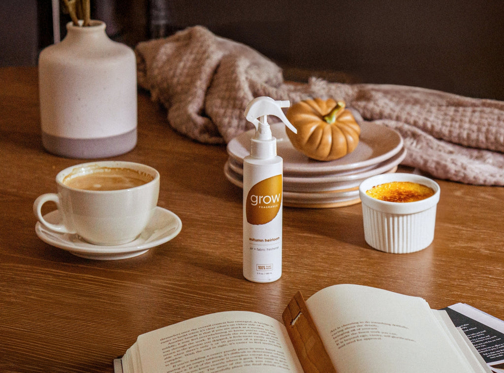 Air and fabric spray bottle with 'grow' logo on wooden table beside cup and book