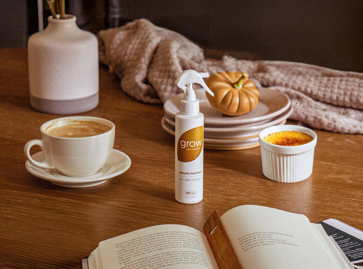 Air and fabric spray bottle with 'grow' logo on wooden table beside cup and book