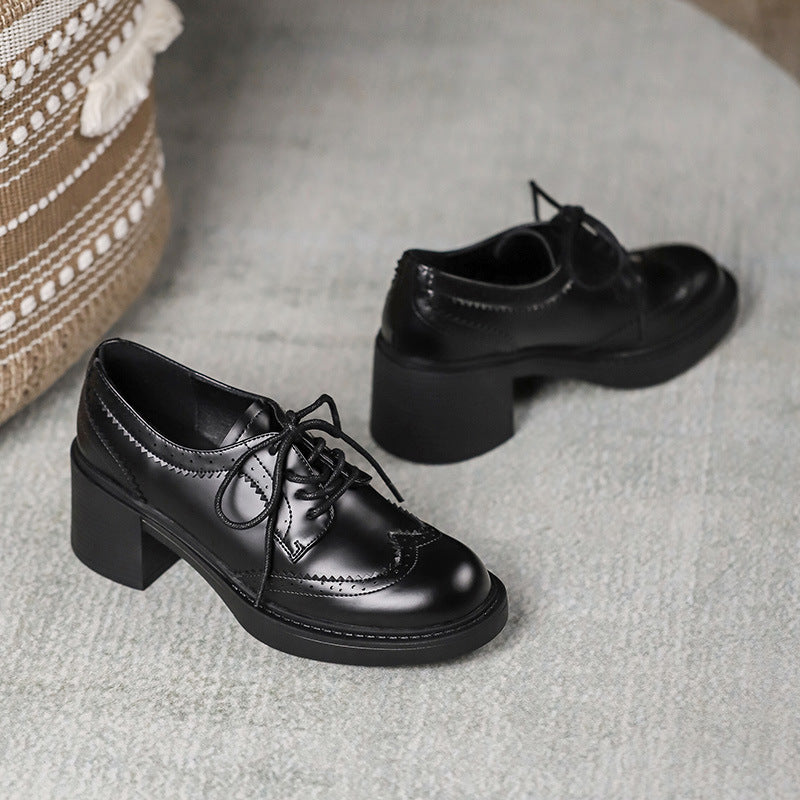 Black lace-up oxford shoes with chunky block heel and glossy upper.