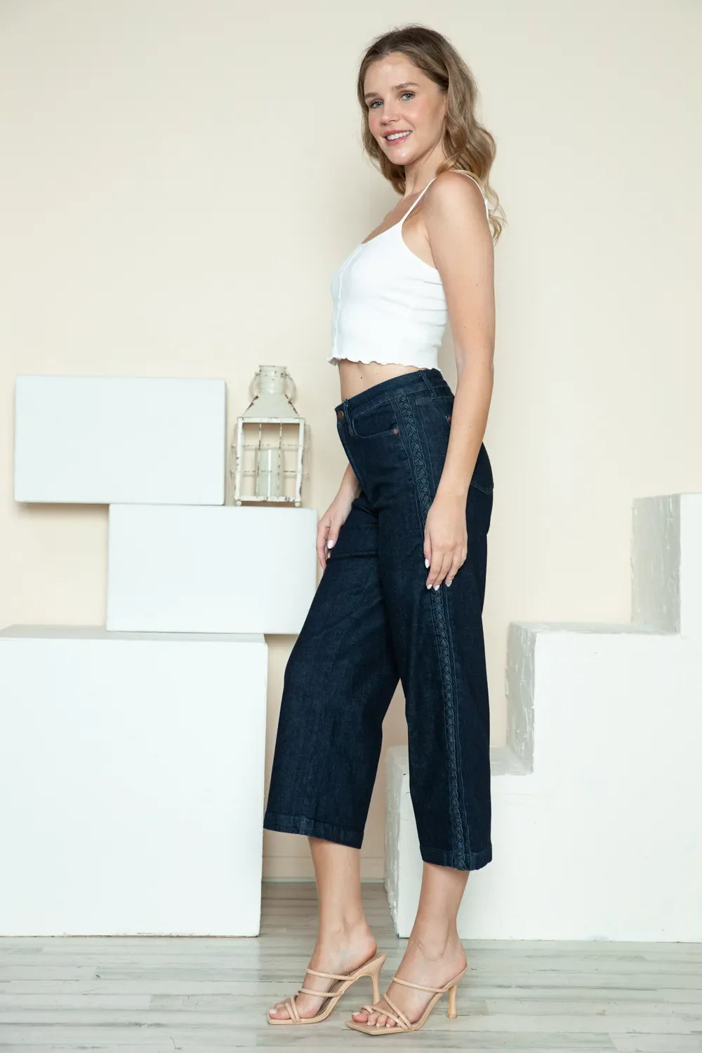 Dark wide-leg cropped jeans with side braid detail, angled side view