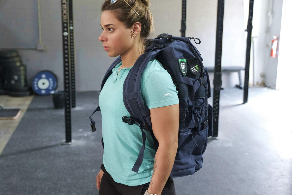 Black military backpack with padded straps and front utility pockets on a person