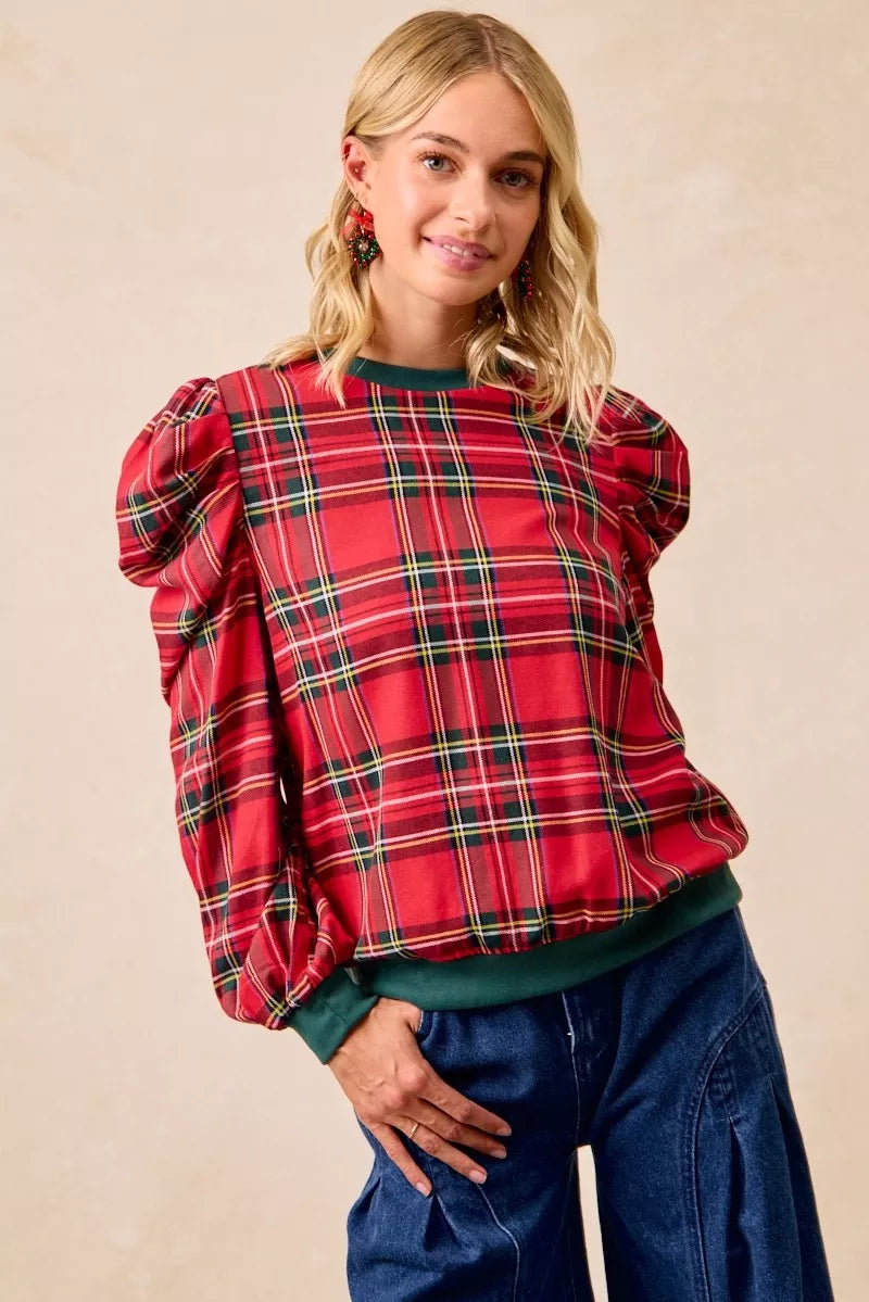 Red plaid blouse with voluminous puff shoulders and green hemline trim