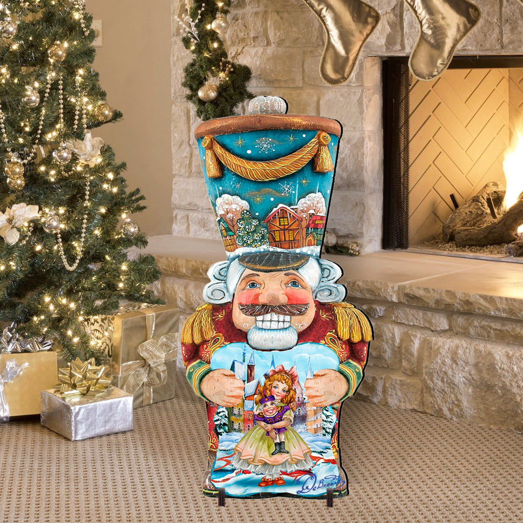 Painted nutcracker outdoor decoration with blue coat, white beard, holding doll
