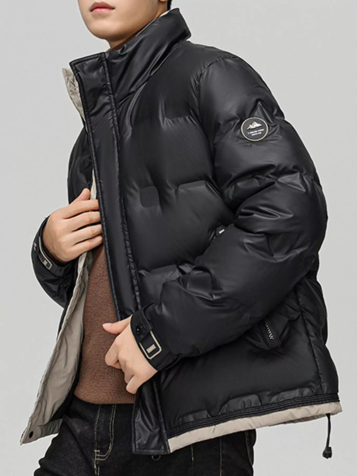 Men's padded lightweight coat in black, angled front, badge patch on sleeve