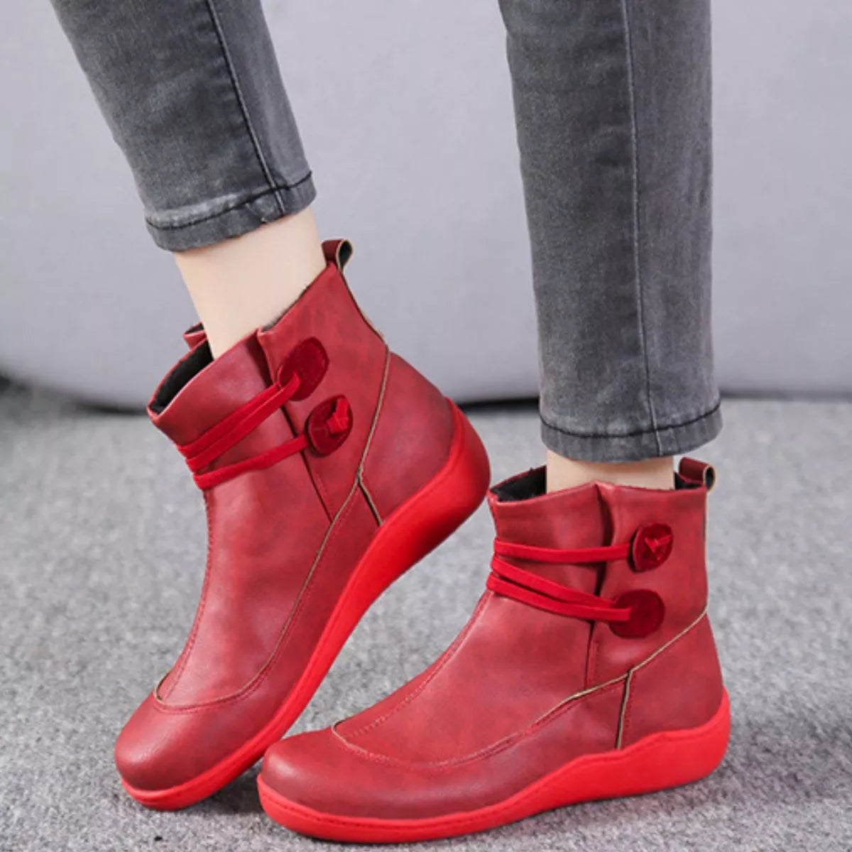 Red lace-up ankle boots with button-detail straps and rounded toe, low sole.