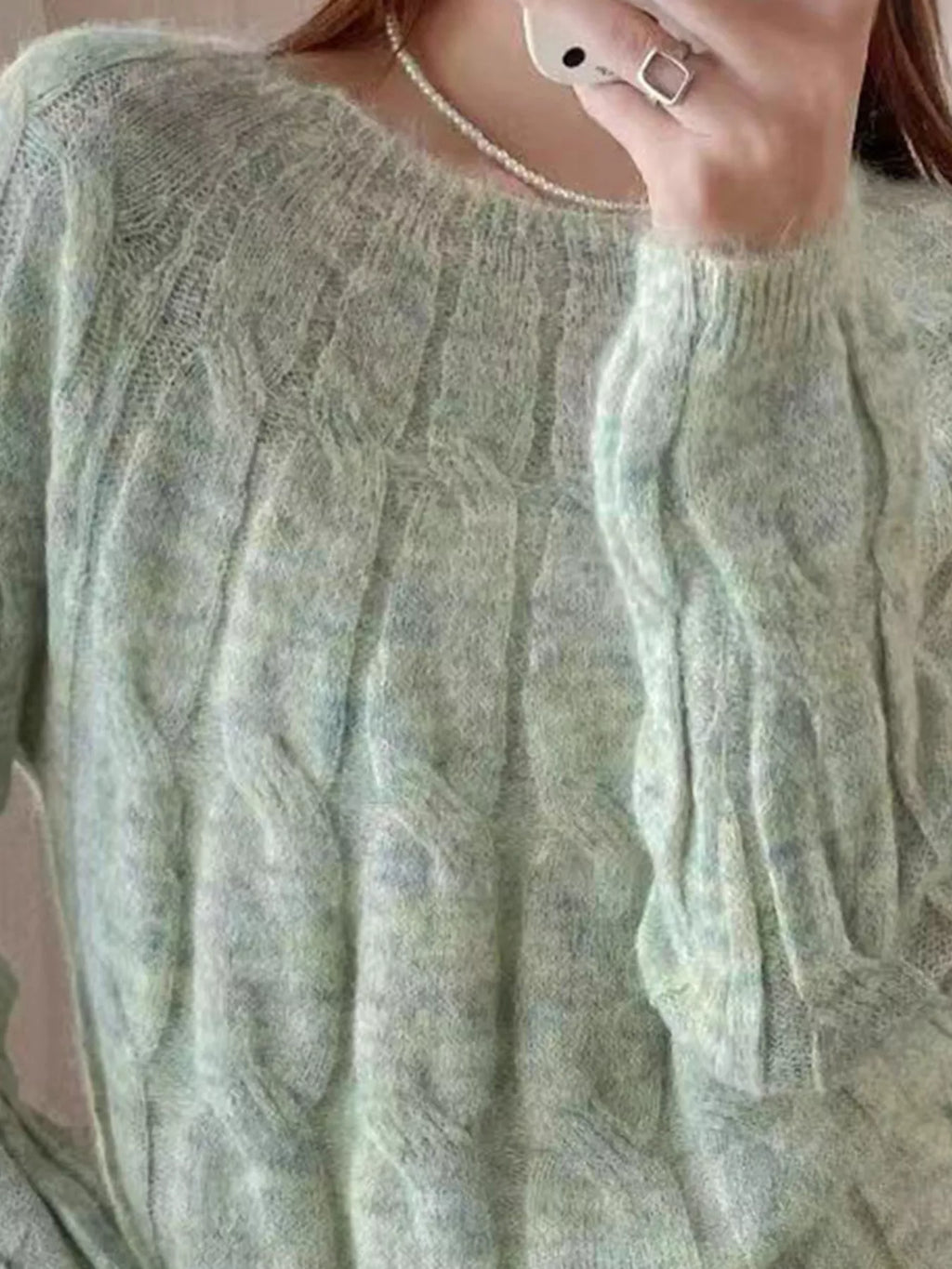Green cable-knit round neck sweater with textured cable pattern