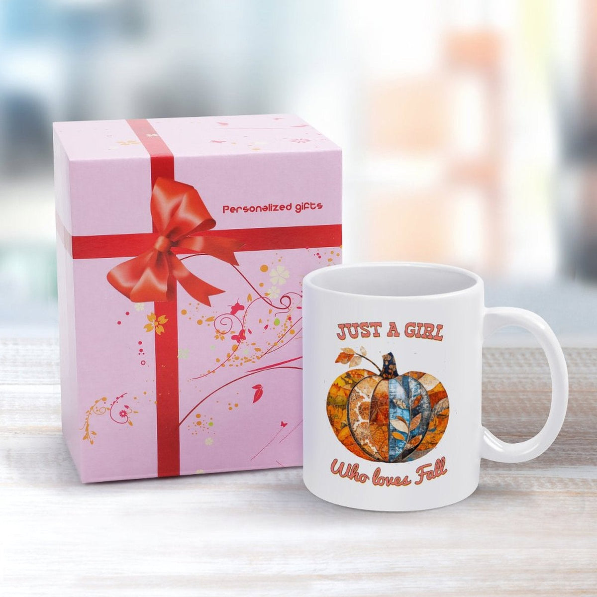 White ceramic mug with handle, pumpkin graphic, next to pink gift box