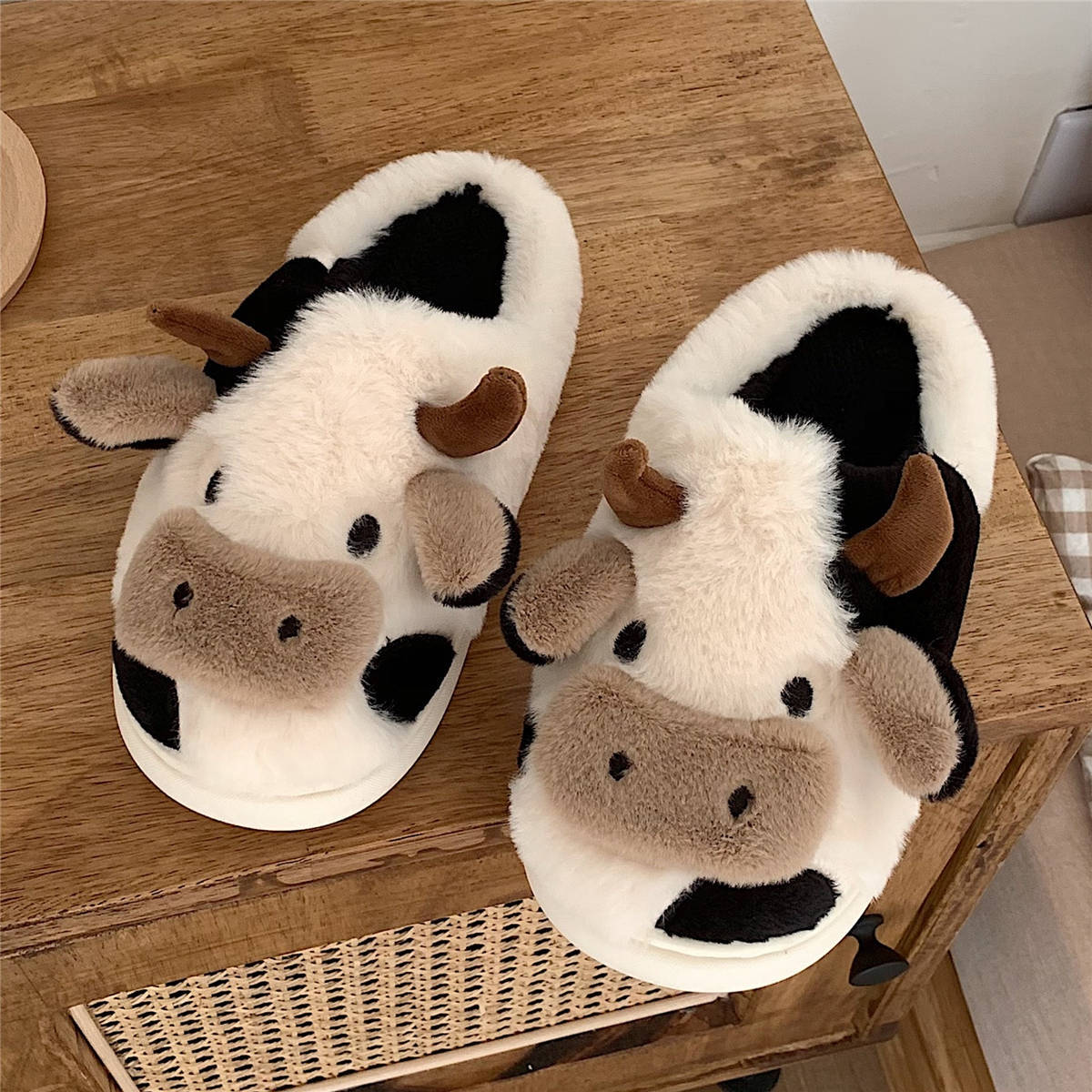 Cow-themed plush slippers with black patches, brown snout, and padded white slide soles